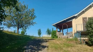 A covered outdoor area with a pathway leading to a building, surrounded by trees and a grassy area. - Gîte Cazette, un coin de Paradis au cœur du Béarn. (Ance Féas)
