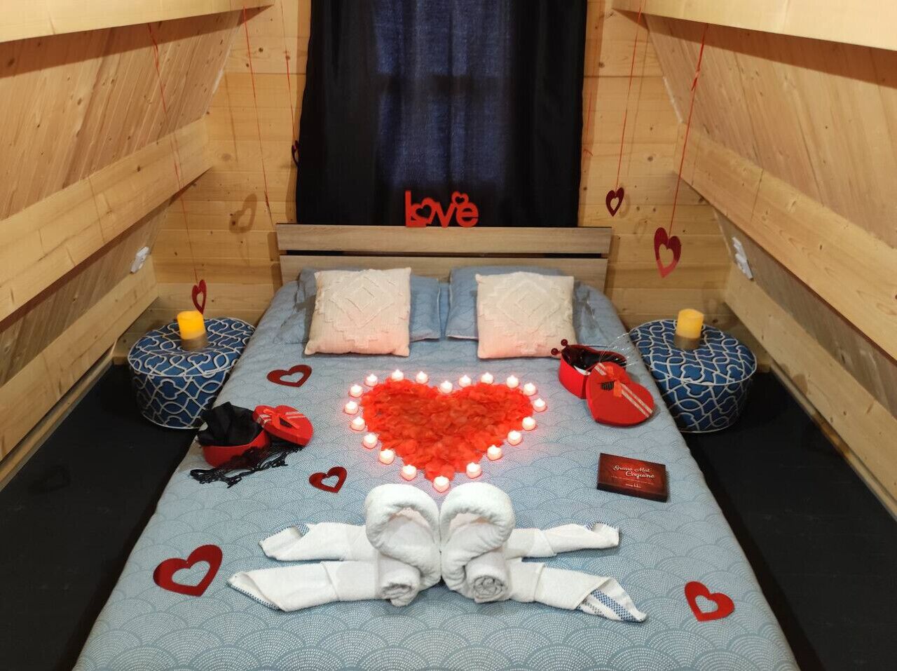 Una habitación acogedora con una cama, decoraciones con forma de corazón y un letrero que dice 'love' en la pared.
