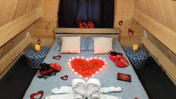 Una habitación acogedora con una cama, decoraciones con forma de corazón y un letrero que dice 'love' en la pared.