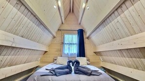 Een gezellige kamer met houten lambrisering, een bed centraal geplaatst, een raam met gordijnen, en een eenvoudig, strak design.