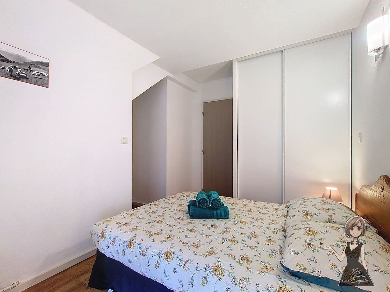 A bedroom with a bed, a nightstand, a lamp, and a wardrobe.