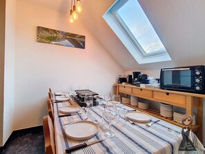 Uma sala de jantar com uma mesa posta para seis pessoas, micro-ondas e prateleira com louças.