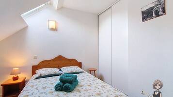 Een slaapkamer met een bed, nachtkastje, lamp, wandlamp en een lijst met een afbeelding.