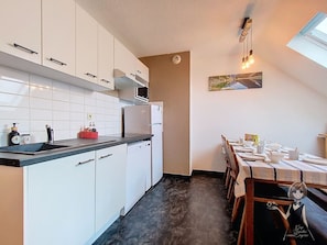 A modern kitchen with white cabinets, a black countertop, and a dining area with a table set for two.