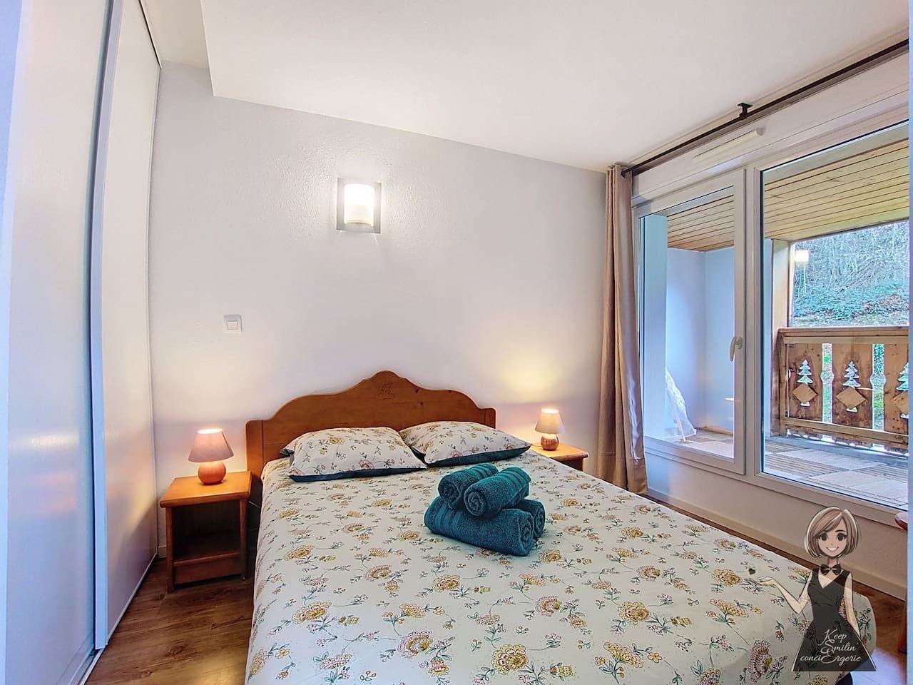 Une chambre à coucher avec un lit, deux lampes de chevet, une fenêtre donnant sur un beau paysage et une petite table avec une lampe.
