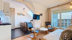 A modern living room with a sofa, two rocking chairs, a small table, and a TV mounted on the wall. - Le Refuge, Cocon pour 8 avec Spa & Piscine chauf. (Cauterets)