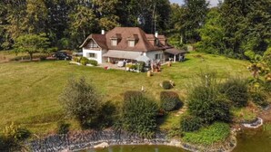 Uma casa grande com gramado bem cuidado e um lago.
