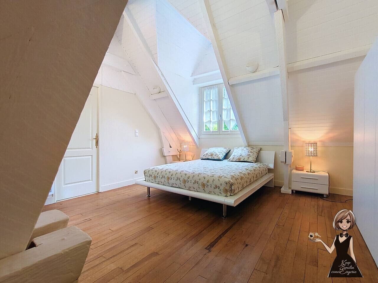 A bedroom with a sloped ceiling, a bed with floral bedding, a nightstand, and a lamp.