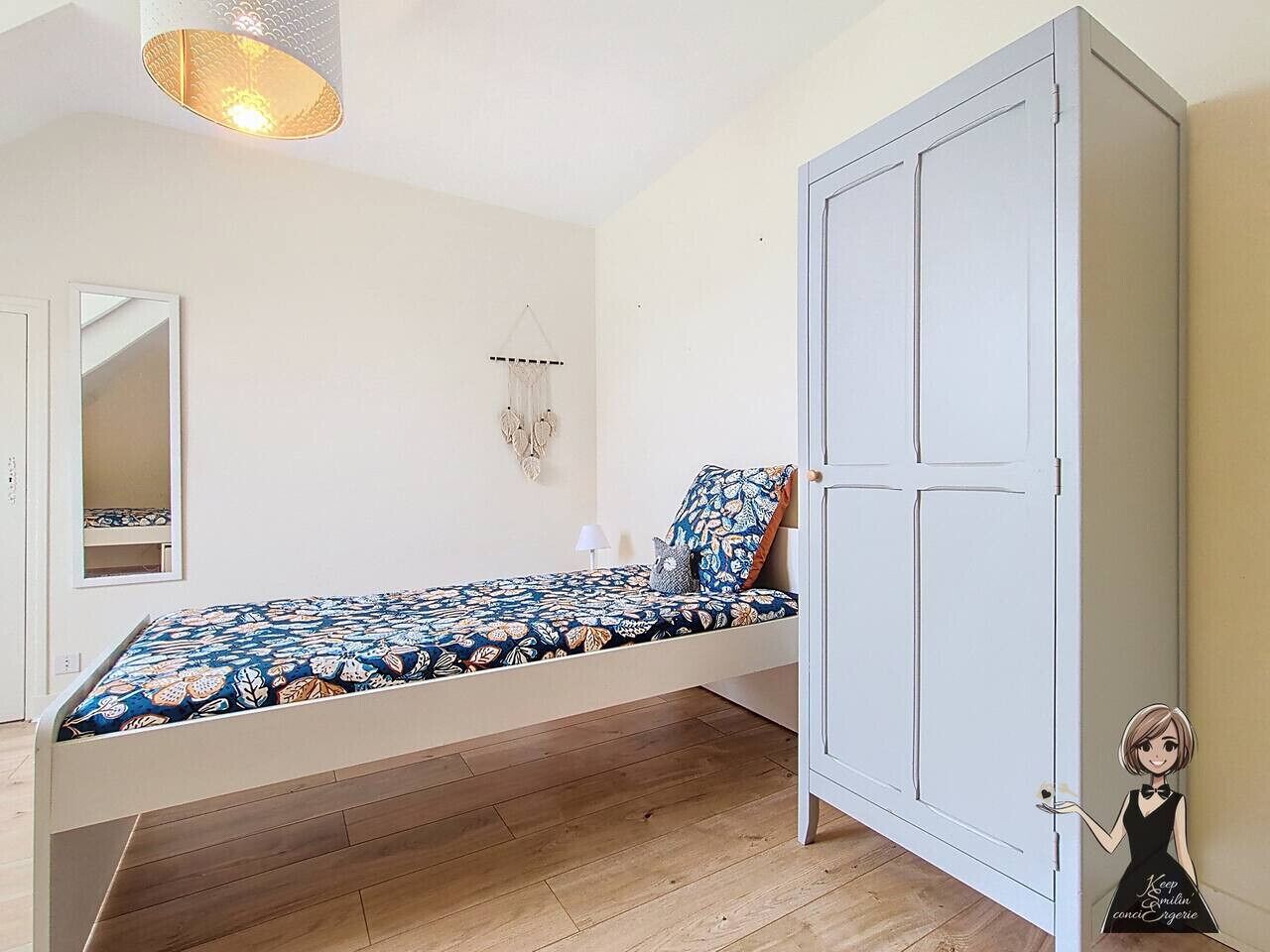 A bedroom with a bed, a wardrobe, a hanging light fixture, and a wall-mounted decorative piece.