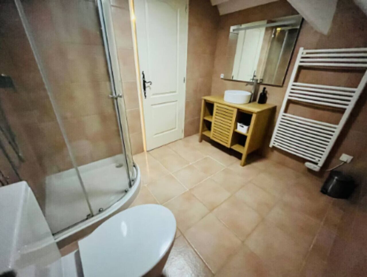 A bathroom with a shower, toilet, sink, and a towel rack.