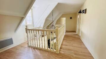 A spacious attic room with a wooden floor, a white railing, and a sloped ceiling.