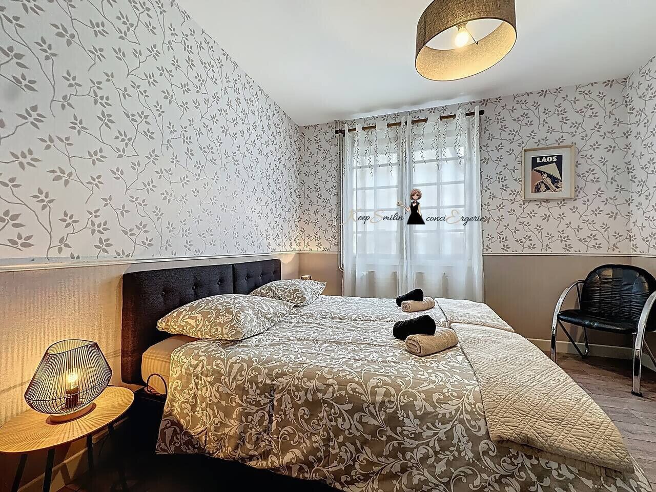 Quarto de hotel com cama, uma cadeira, abajur e janela com cortinas.