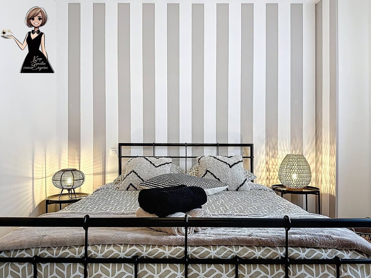 Une chambre à coucher avec un lit, des oreillers, une table de chevet et une lampe fixée au mur.