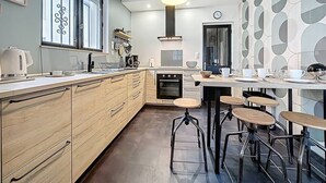 Ett modernt kök med träskåp, en inbyggd ugn och en matplats med barstolar.