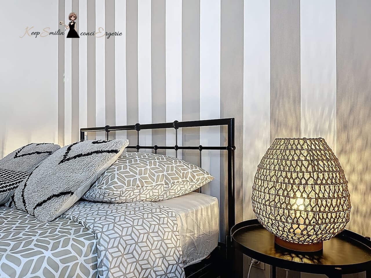 A neatly made bed with patterned bedding and a decorative lamp beside it.