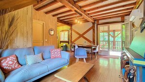 Ein gemütliches Wohnzimmer mit einem blauen Sofa, Holzbalken und einem Klavier.