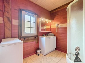 A compact bathroom with wooden walls, a window, a sink with a towel rack, and a toilet.