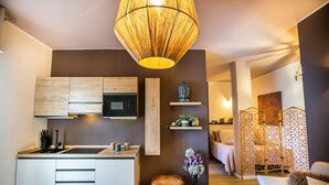 A modern kitchen with wooden cabinets, a built-in microwave, and a central island. There is a decorative vase with flowers on the floor next to the island. - 10 Floor Apartments (Como)
