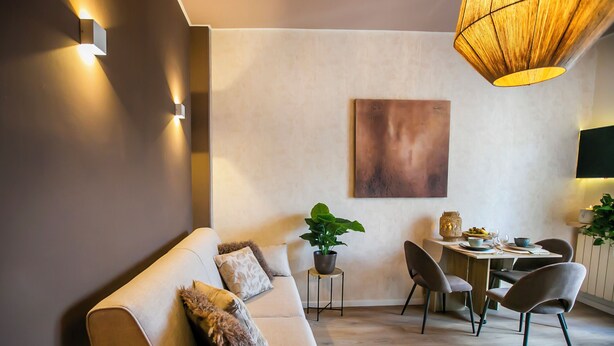A modern living room with a sofa, dining table, chairs, and a hanging light fixture. - 10 Floor Apartments (Como)
