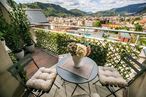 A balcony with a cushioned chair, a small table, and a potted plant. - 10 Floor Apartments (Como)