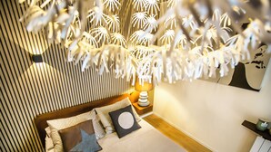 A modern bedroom with a bed, pillows, a bedside table with a lamp, and a wall-mounted shelf. - 10 Floor Apartments (Como)