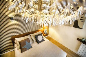 A modern bedroom with a bed, pillows, a bedside table with a lamp, and a wall-mounted shelf. - 10 Floor Apartments (Como)