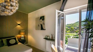 A modern bedroom with a bed, bedside table, lamp, and a view of a balcony. - 10 Floor Apartments (Como)