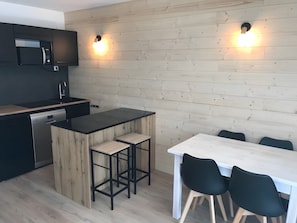Eine moderne Küche mit eingebauter Mikrowelle, einem Geschirrspüler und einer Holztischinsel mit Barhocker.