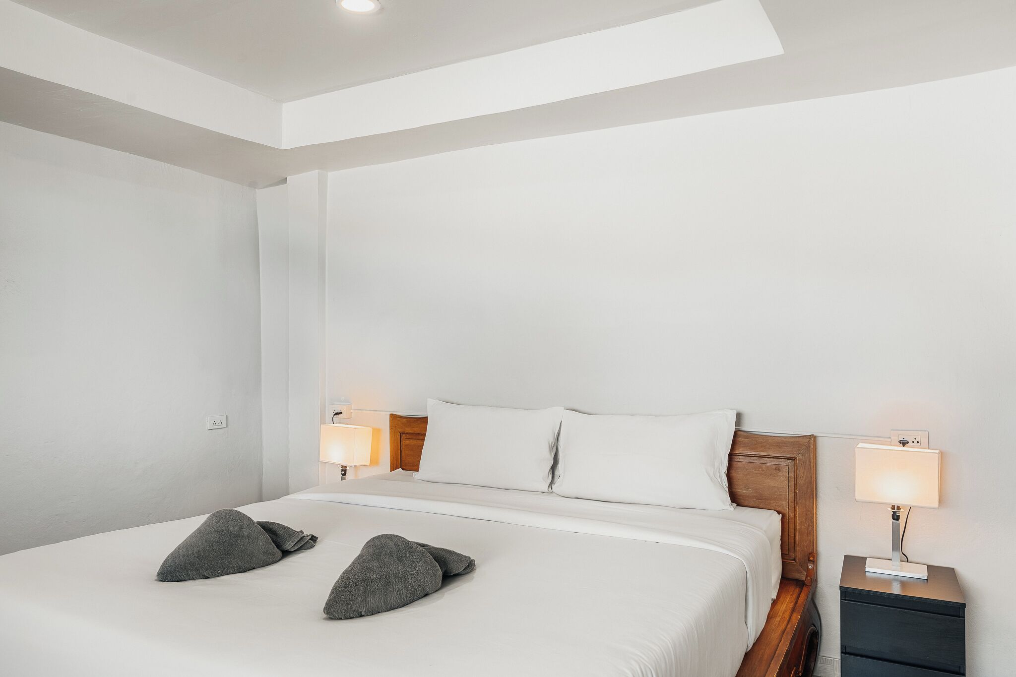 Un letto rifatto con cuscini, una lampada da comodino e un comodino.