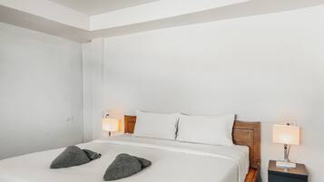 A neatly made bed with pillows, a bedside lamp, and a nightstand.