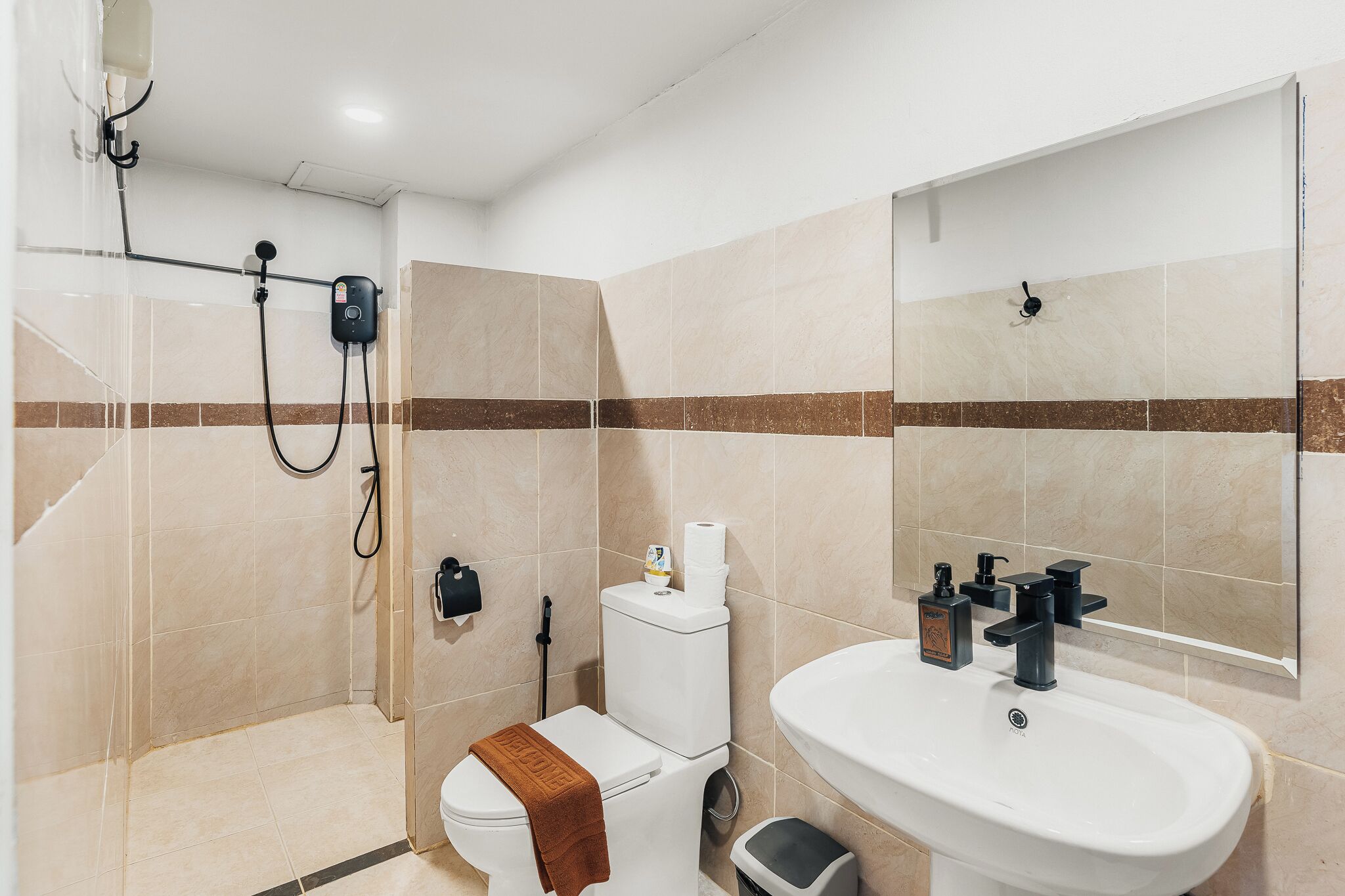 Une salle de bain équipée d’une douche, de toilettes, d’un lavabo et d’un miroir.