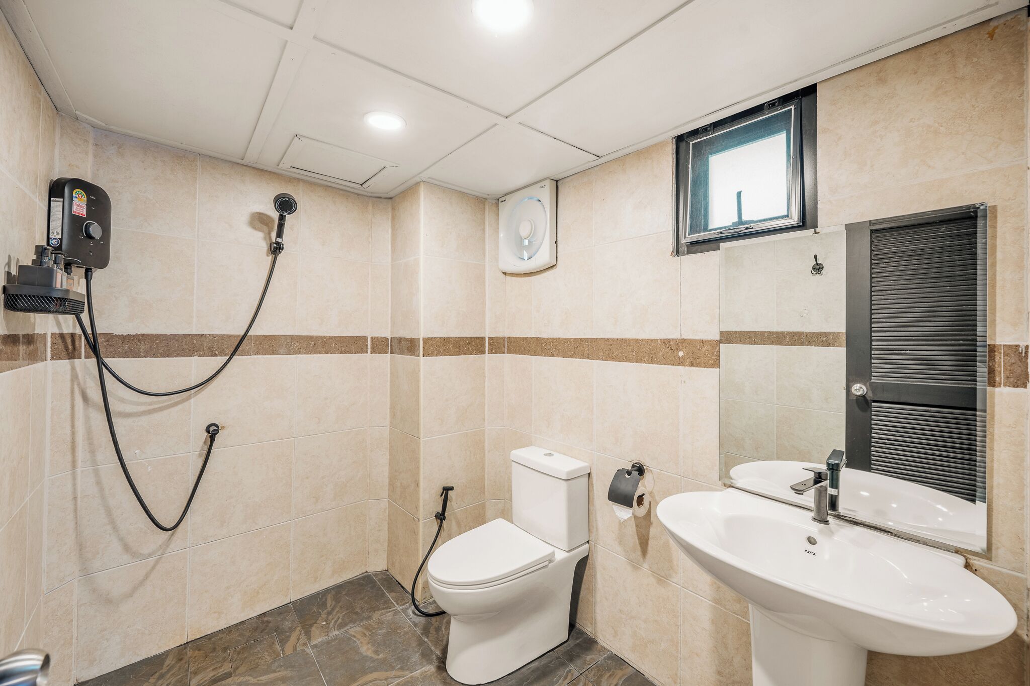 A bathroom with a toilet, bidet, sink, and a window.