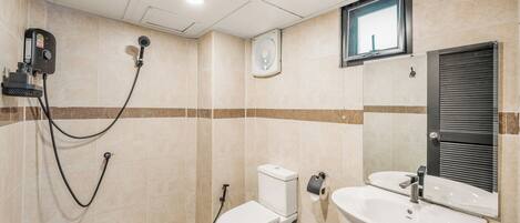 A bathroom with a toilet, bidet, sink, and a window.