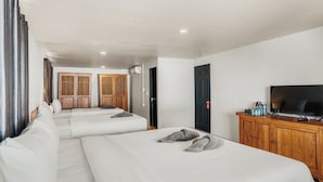 A hotel room with two beds, a TV, a wooden cabinet, and a wardrobe.