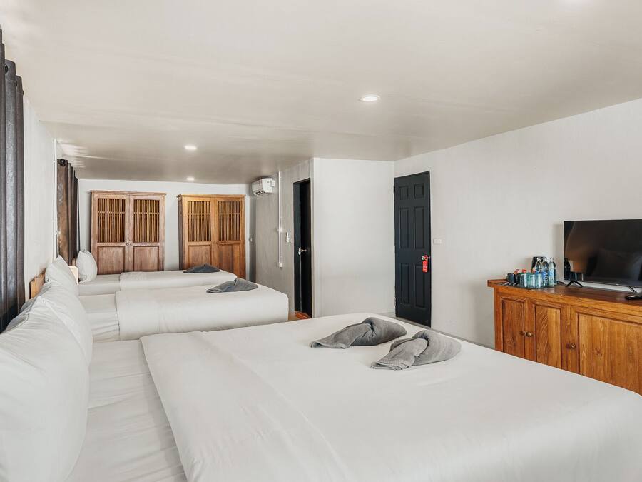 Una habitación de hotel con dos camas, televisión, aparador de madera y armario.