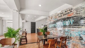 A modern dining area with a brick wall mural, wooden chairs, and a tiled floor.