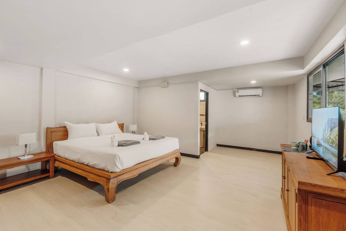 A bedroom with a wooden bed, bedside tables, a TV, and a view of the outdoors.