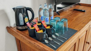 A kitchen counter with a coffee maker, water bottles, glasses, and utensils.