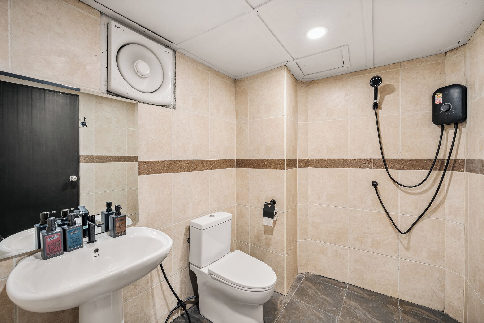 Une salle de bain équipée d’un lavabo, de toilettes, d’une douche et d’un radiateur fixé au mur.