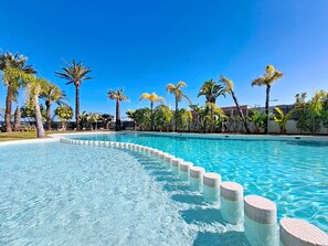 A clear blue pool with a tiled edge, surrounded by palm trees and a fence. - Bright Apartment with Expansive Poolside Balcony (Mar de Cristal)