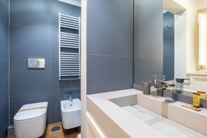 Une salle de bain moderne équipée de toilettes, d’un bidet et d’un grand miroir.