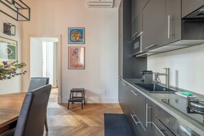Une cuisine moderne équipée d’appareils électroménagers en acier inoxydable, une table à manger en bois et un petit tabouret.