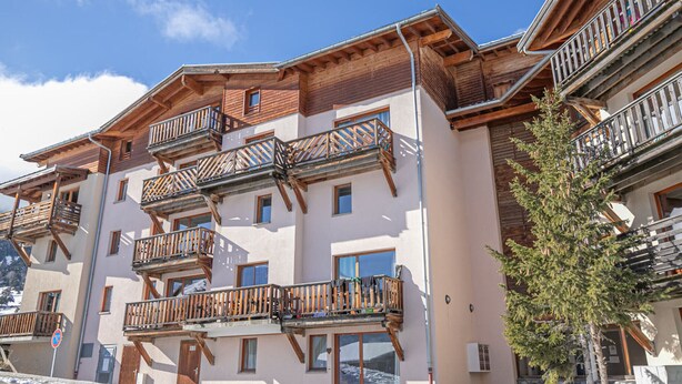 Un hotel de varios pisos con balcones de madera y fachada de piedra.