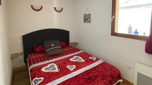 Un dormitorio con cama, ventana y un cuadro colgado en la pared.