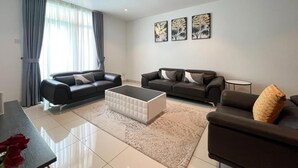 Ein modernes Wohnzimmer mit zwei schwarzen Sofas, einem weißen Couchtisch und einem gemusterten Teppich.