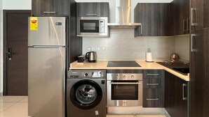 Eine moderne Küche mit Edelstahl-Kühlschrank, Mikrowelle, Backofen und Waschmaschine.