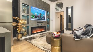 A modern living room with a flat-screen TV, a fireplace, a sofa, and decorative plants. - Private Luxury Spa Suite: Sauna, Jacuzzi, Ice Bath (Burton upon Trent)