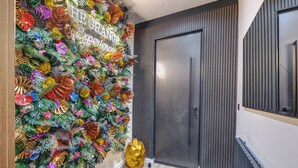 A modern interior with a decorative wall of colorful paper flowers and a golden geometric sculpture. - Private Luxury Spa Suite: Sauna, Jacuzzi, Ice Bath (Burton upon Trent)