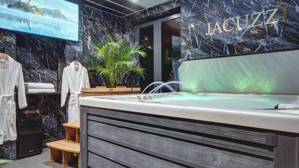 A modern bathroom with a marble wall, a large mirror, and a jacuzzi tub. - Private Luxury Spa Suite: Sauna, Jacuzzi, Ice Bath (Burton upon Trent)