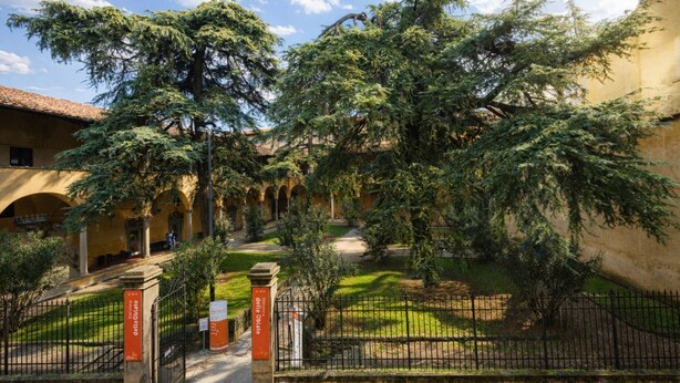 Un patio con una fuente, un camino y un edificio con arcos.